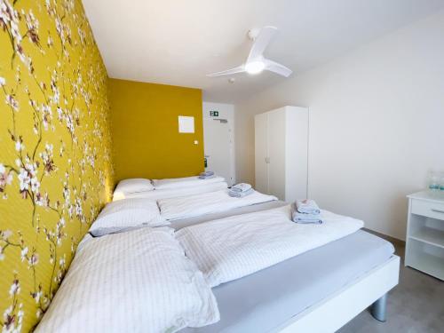 a bedroom with three beds against a yellow wall at Pension Voesendorf in Vösendorf