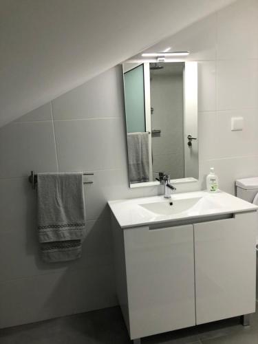 a white bathroom with a sink and a mirror at Casa das Palmeiras in Calheta