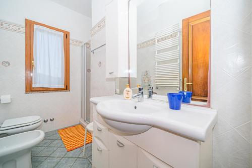 uma casa de banho branca com um lavatório e um WC em Appartamento villa da 4 fino a 5 persone giardino em Capoliveri
