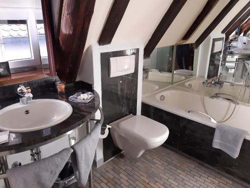 La salle de bains est pourvue d'un lavabo, de toilettes et d'une baignoire. dans l'établissement Hotel Schiefes Haus, à Ulm