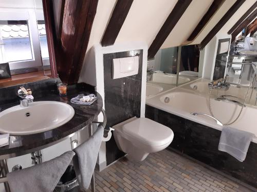 a bathroom with a sink and a toilet and a tub at Hotel Schiefes Haus in Ulm