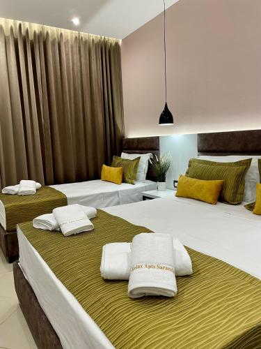 two beds in a hotel room with towels on them at Relax Apts Saranda in Sarandë
