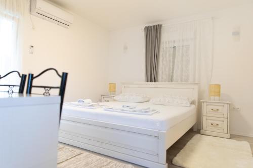 a white bedroom with a white bed and a window at Apartment Kravica in Ljubuški