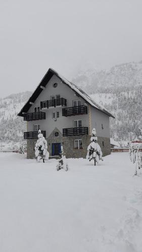 a large building in the snow with snow covered trees at Guesthouse Drinos Valbone in Valbonë