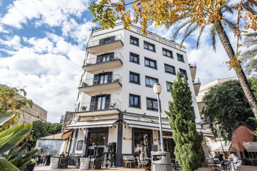 un edificio blanco alto con gente sentada fuera de él en Hostal Parque Ibiza en Ibiza