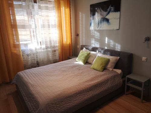a bedroom with a bed with two green pillows at Apartament Marzenie 10 - Opole in Opole