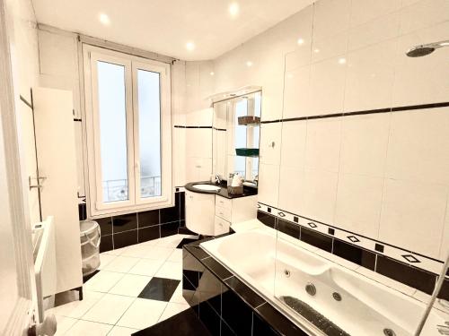 une salle de bain blanche avec une baignoire et un lavabo dans l'établissement Joli appartement spacieux à 3 min à pied de la mer, à Nice