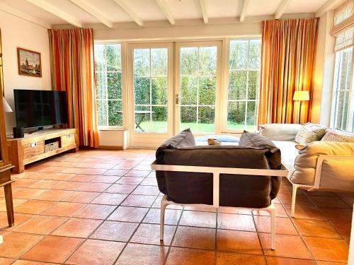a living room with a couch and a tv at Uniek huis onderaan de duinen -veel privacy- eigen parkeerplaats in Domburg