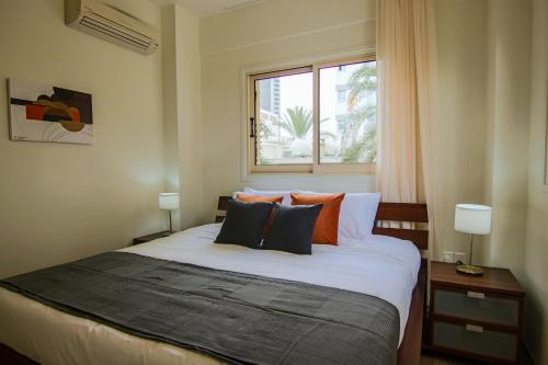 1 dormitorio con cama con almohadas y ventana en Phaedrus Living City View Luxury Iras Flat 102, en Nicosia