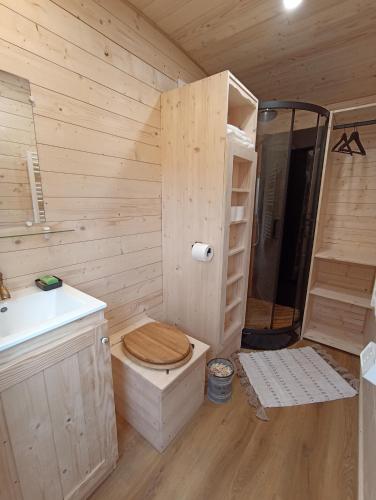 La salle de bains en bois est pourvue de toilettes et d'un lavabo. dans l'établissement Roulottes Les Alpaguettes, à Saint-Romain-de-Benet