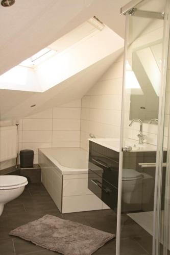 a bathroom with a sink and a tub and a toilet at Gästehaus Mittendrin in Dahn
