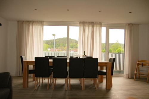 a dining room table with black chairs and a large window at Gästehaus Mittendrin in Dahn