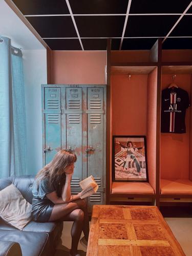 a woman sitting on a couch reading a book at Greet Boulogne Billancourt Paris in Boulogne-Billancourt