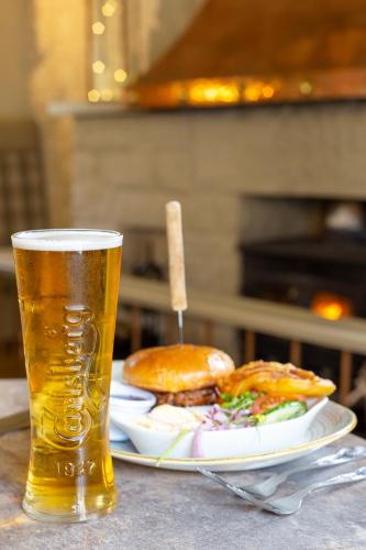 a glass of beer sitting next to a plate of food at The Stair Arms Hotel in Edinburgh
