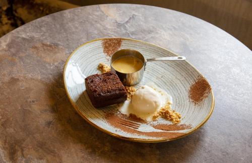 a plate with a piece of cake and ice cream at The Stair Arms Hotel in Edinburgh