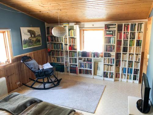 a room with a chair and book shelves with books at Jacobs Stuga in Furudal