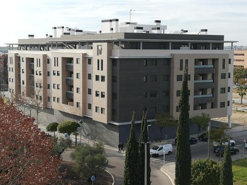 un gran edificio con coches estacionados frente a él en Apartamento Servet, parking gratuito, a 5 minutos de Sevilla, en Bormujos