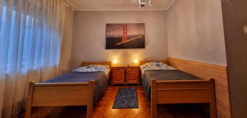 two beds in a room with a bridge picture on the wall at NOCLEGI U IRENKI in Koło