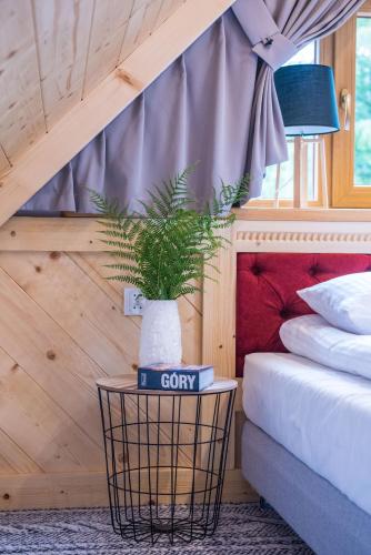 a potted plant sitting on a table next to a bed at Willa pod Orłem - Zakopane in Zakopane
