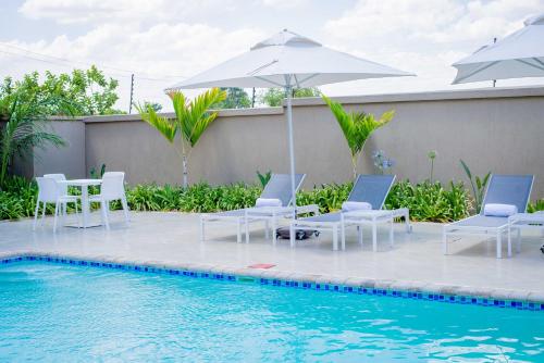 - une piscine avec des chaises longues et des parasols à côté de la piscine dans l'établissement Lalibela Boutique Hotel, à Lilongwe
