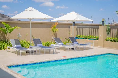 a swimming pool with two chairs and umbrellas next to a pool at Rosewood by Amaryllis Lilongwe in Lilongwe
