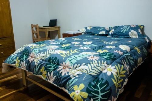 Una cama con una manta azul con flores. en Casa Libertad, en Cusco