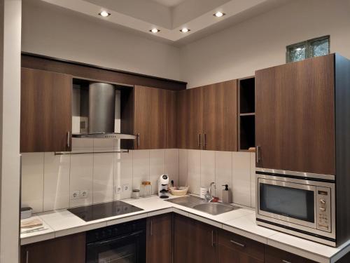 a kitchen with wooden cabinets and a microwave at Lovely Apartment with free parking in Kecskemét