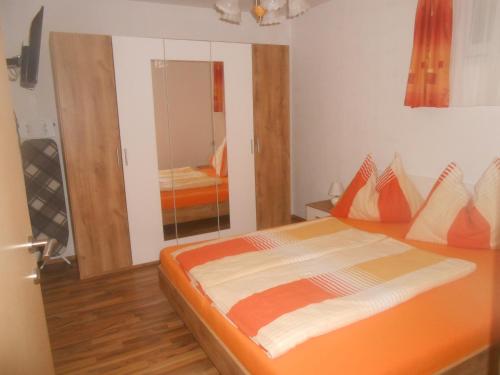 a bedroom with an orange bed and a mirror at Ferienwohnung Michaela in Flattach