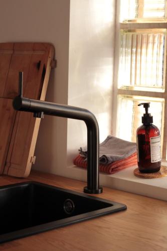 a sink with a bottle of soap next to a window at Ferienturm zur ehemal. Umspannstation Poppenroth in Bad Kissingen