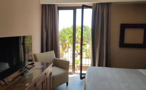 a hotel room with a bed and a tv and a balcony at Araja Villa&Suite by Geocharme in San Vito lo Capo