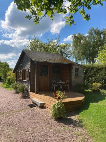 eine kleine Hütte mit einer Holzterrasse und einem Tisch in der Unterkunft Domaine des Thyllères,Chalet Colvert in Beaufour