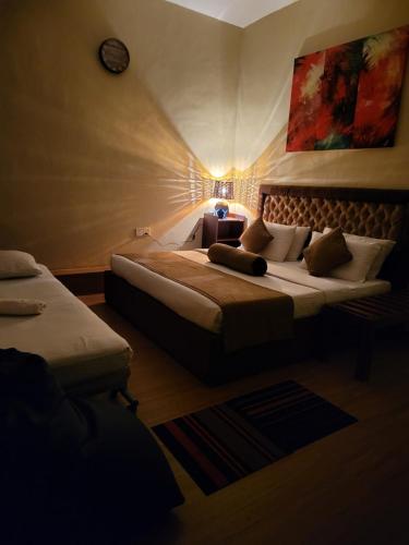 a hotel room with two beds and a clock on the wall at Hill Cool Hotel & Restaurant in Hatton
