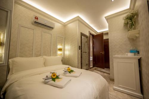 A Residence @ Between Hilton & Cititel Hotel في كوتا كينابالو: غرفة نوم بسرير ابيض كبير عليها صحنين
