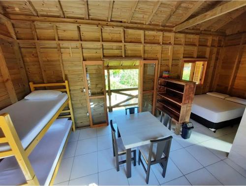 Zimmer mit 2 Etagenbetten sowie einem Tisch und Stühlen in der Unterkunft Canto da Aracuã in Praia do Rosa