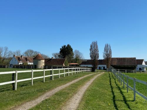 un chemin de terre dans un champ avec une clôture blanche dans l'établissement Domaine de Prestal, à Le Merlerault
