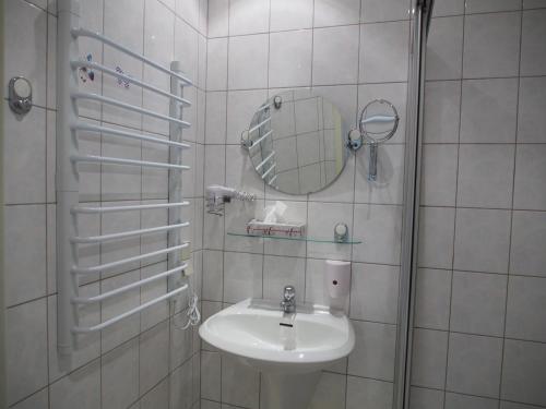 a white bathroom with a sink and a mirror at Altes Teichhaus - Pension Ottendorf-Okrilla in Ottendorf-Okrilla