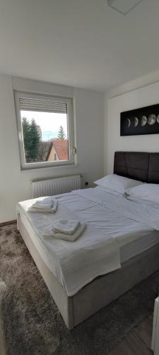 a white bedroom with a large bed and a window at Perfect Place 32 in Varaždin