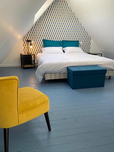 a bedroom with a large bed and a yellow chair at Les Apparts in Genneville