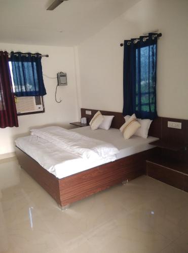 a large bed in a bedroom with blue curtains at Corbett Bhavesh home Stay in Jhirna