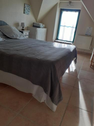 a bedroom with a large bed with a window at Les Gites de Kerdurod in Guidel