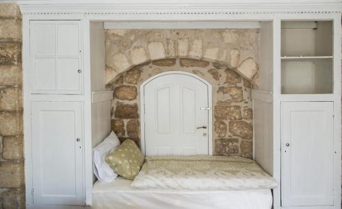 a bed in a room with a stone wall at Alexandra House in Nazareth