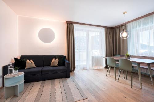 a living room with a black couch and a table at Residence Königswarte Strata Sexten in Sesto