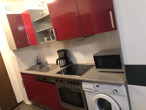 a small kitchen with red cabinets and a washing machine at B507, Schönes und gemütliches Appartement in Lahnstein