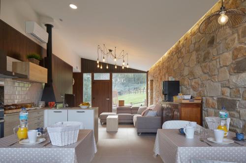 uma cozinha e sala de estar com mesas e uma parede de pedra em Casa Rural Akei - Basque Stay em Elgóibar