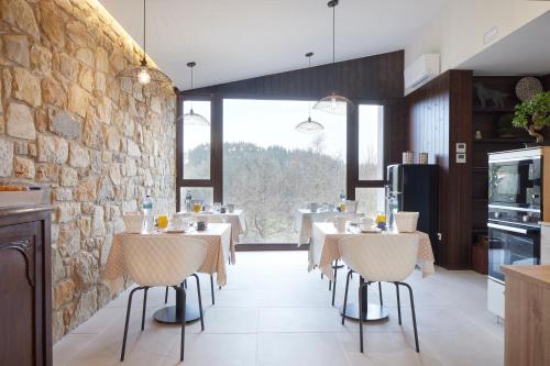 ein Restaurant mit Tischen und Stühlen und einer Steinmauer in der Unterkunft Casa Rural Akei - Basque Stay in Elgóibar