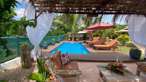 a swimming pool in a yard with chairs and an umbrella at LA CASE BOIS CRÉOLE in Albion