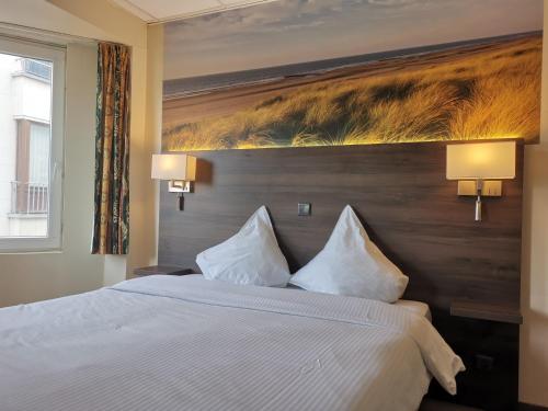 a bedroom with a large bed with two white pillows at Hotel Albert II Oostende in Ostend