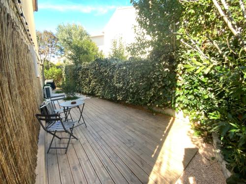 eine Holzterrasse mit 2 Stühlen und einem Tisch in der Unterkunft Belle chambre au calme centre Montpellier in Montpellier