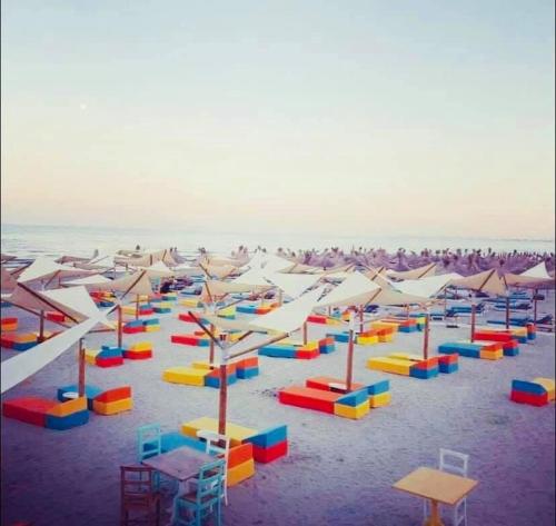 a beach with many colorful chairs and umbrellas at Alezzi Seaside in Năvodari