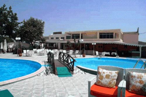 a large swimming pool with chairs and a building at Achillion Palace in Kalambaki